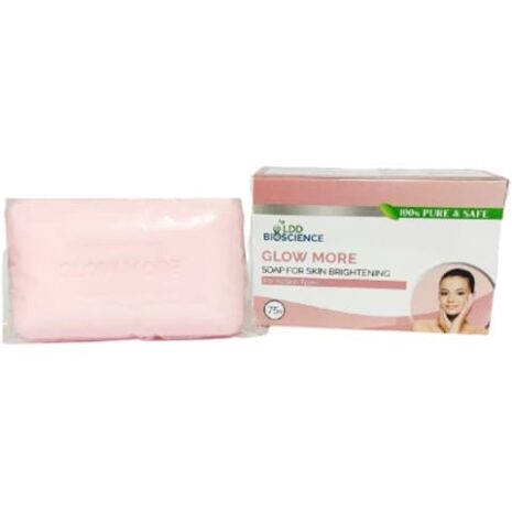 A pink bar soap with packaging that promotes skin brightening, featuring the text "Glow More" and an image of a smiling woman.